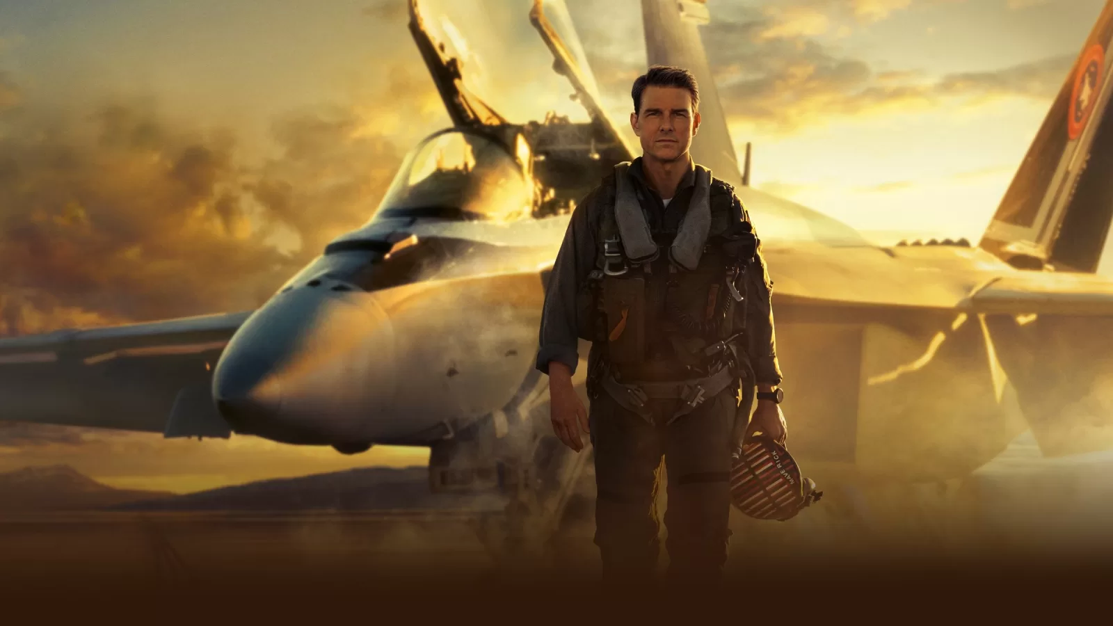 Un piloto con uniforme de vuelo camina sobre la pista frente a un avión de combate F/A-18 al atardecer